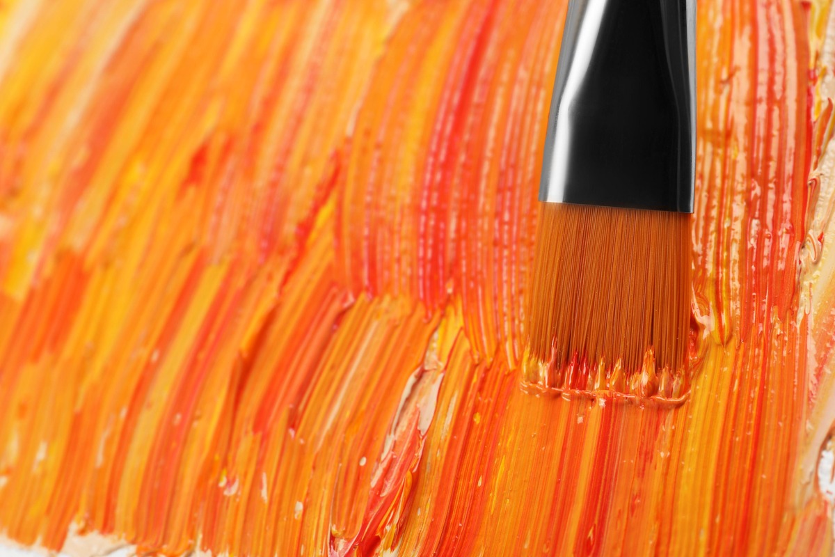 ORANGE, color psychology: Applying colorful oil paints with brush on canvas, closeup